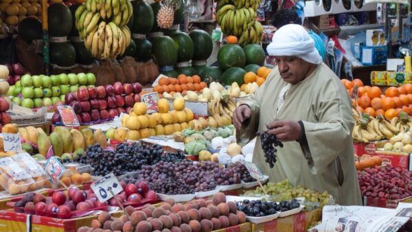 مواطن يُعاين الفاكهة في سوق شعبي للخضار والفاكهة في مصر.